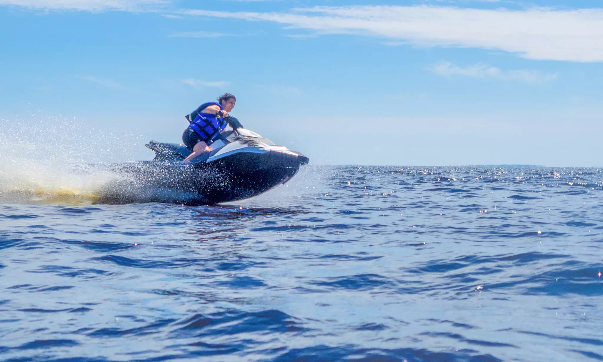 Person riding a jet ski at high speed on the Gulf near Pensacola.